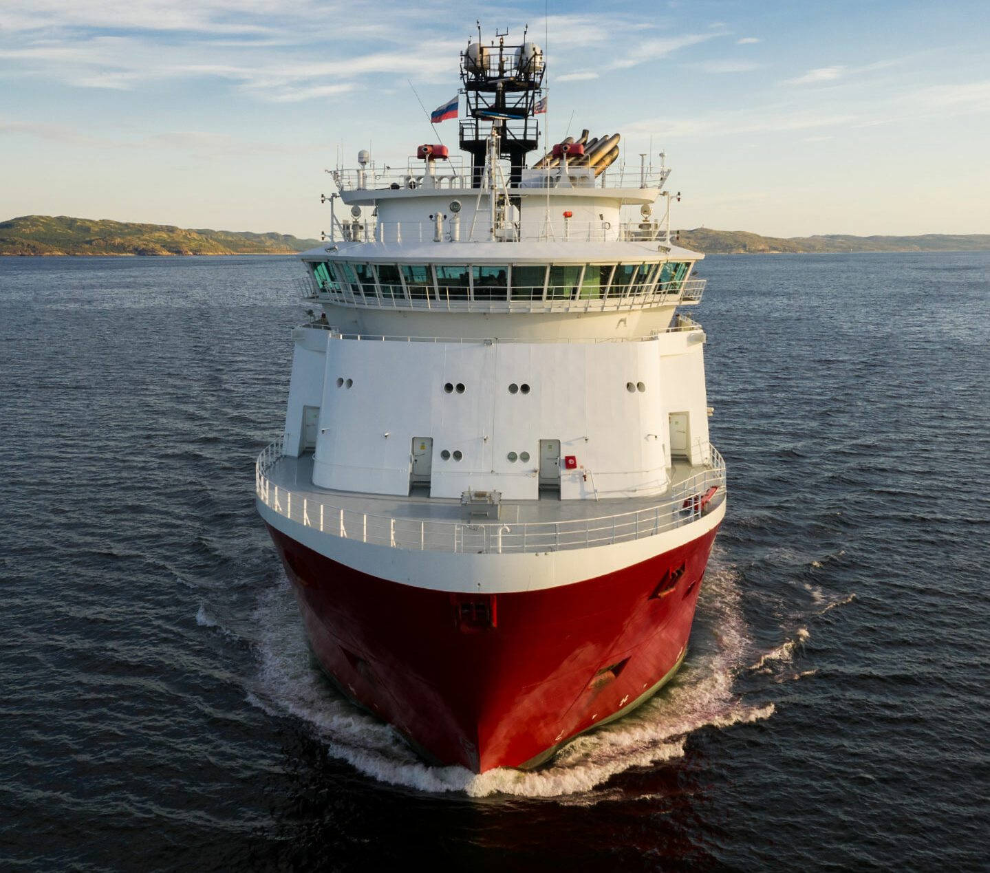 Large red and white ship near the coast.