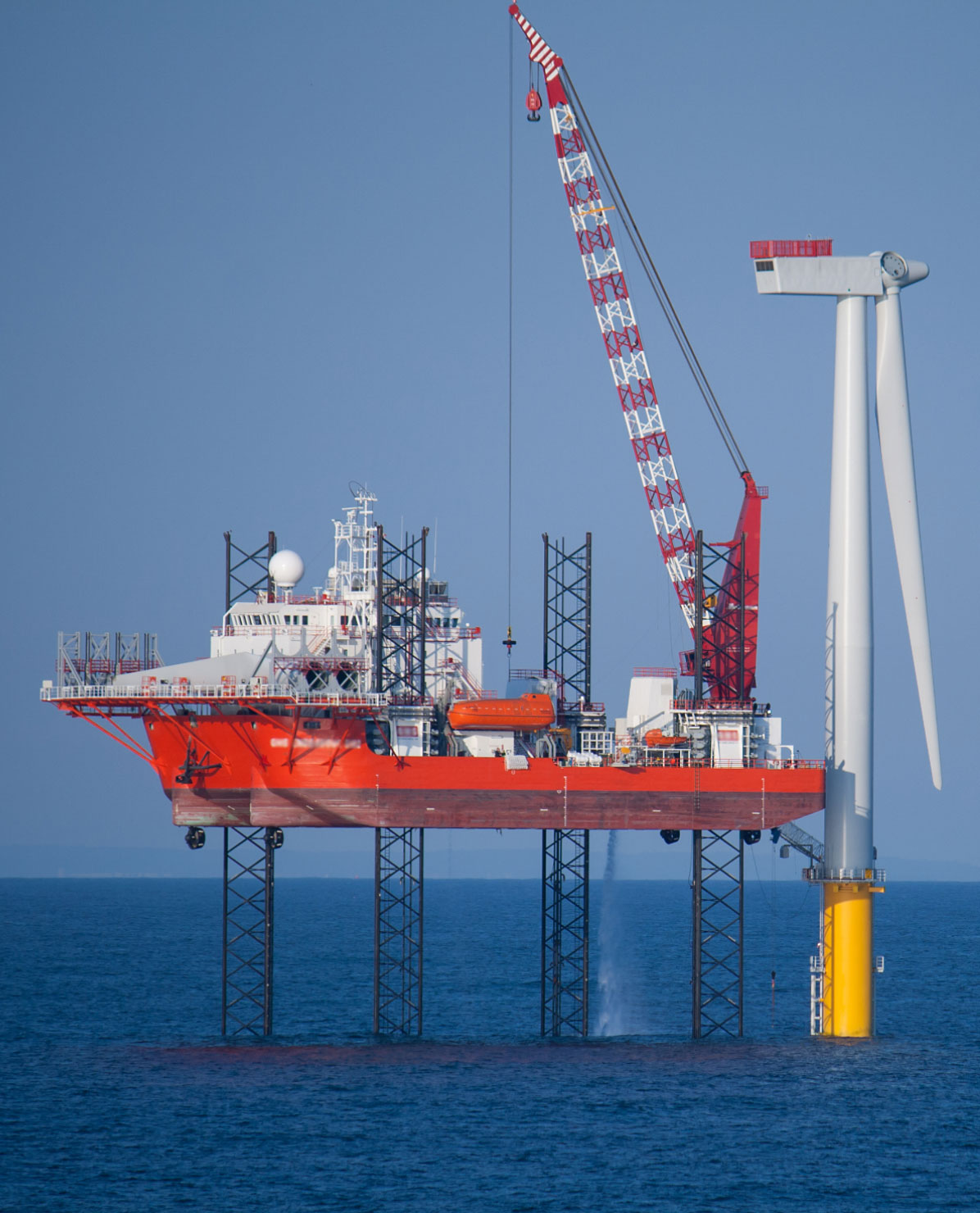 Working rig next to a wind turbine in the ocean.